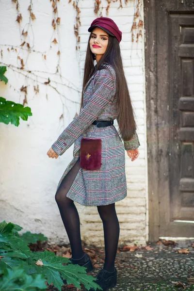Junge schöne Frau mit sehr langen Haaren trägt Wintermantel und Mütze im Herbst Blätter Hintergrund — Stockfoto