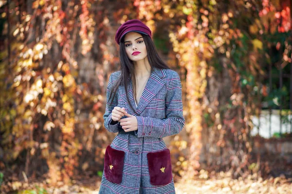 Joven hermosa mujer con pelo muy largo con abrigo de invierno y gorra en el fondo de las hojas de otoño — Foto de Stock