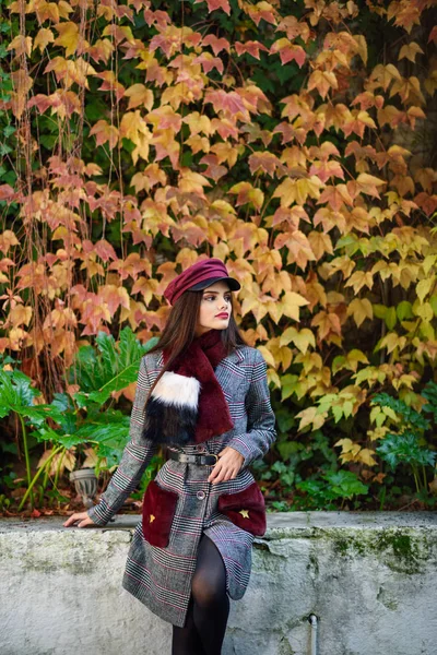 Joven hermosa chica con el pelo muy largo con abrigo de invierno y gorra en el fondo de las hojas de otoño —  Fotos de Stock