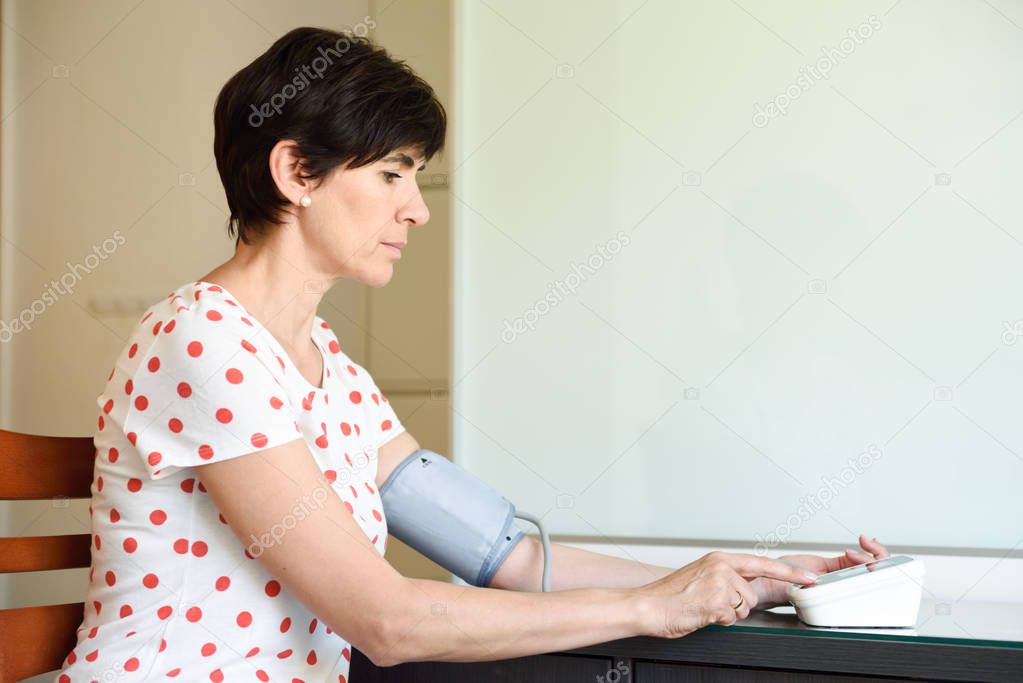 Woman measuring her own blood pressure at home.