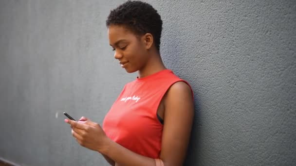 Jonge zwarte vrouw texting met haar slimme telefoon in stedelijke achtergrond. — Stockvideo