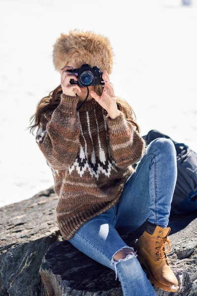 Giovane donna che scatta fotografie sulle montagne innevate — Foto Stock