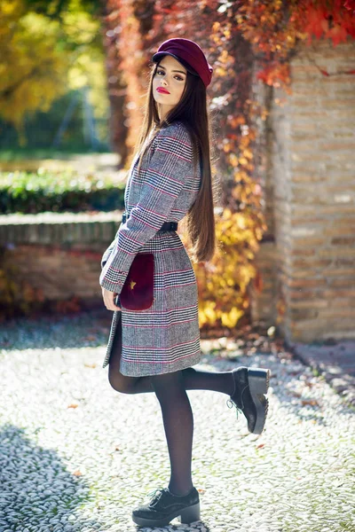 Joven hermosa chica con abrigo de invierno y gorra en el fondo de hojas de otoño. — Foto de Stock