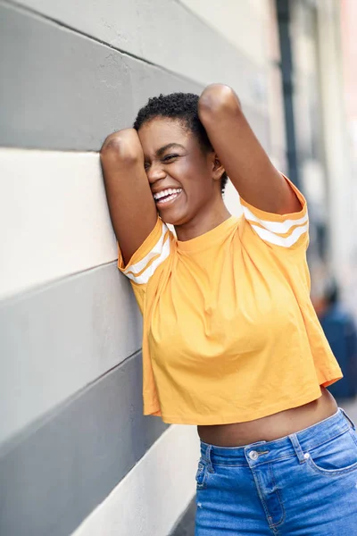 Boldog fekete nő nevetve a városi falon. — Stock Fotó