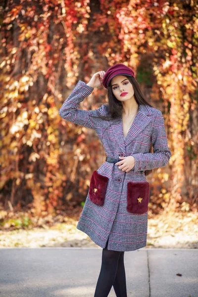 Joven hermosa chica con abrigo de invierno y gorra en el fondo de hojas de otoño. —  Fotos de Stock