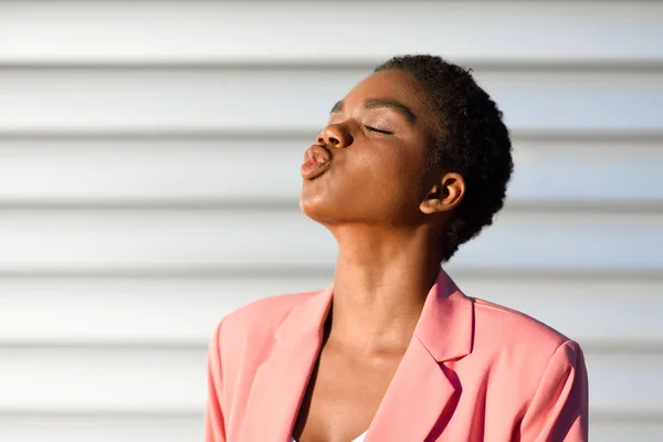 Femme noire, aux cheveux très courts soufflant un baiser . — Photo