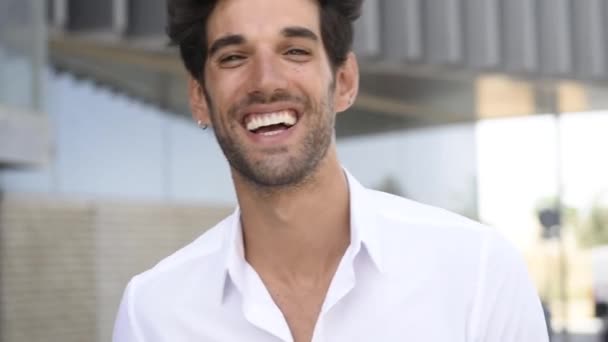 Mladý muž se usmívá na kameru oblečenou v neformální šatech s moderním účesu. — Stock video
