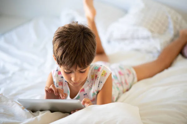 Petite fille jouant avec tablette numérique sur le lit . — Photo