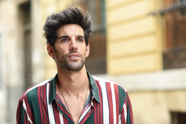 Attractive young man with dark hair and modern hairstyle wearing casual clothes outdoors — Stock Photo, Image