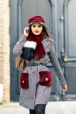 Çok uzun saçlı genç güzel kız kış ceket ve şapka açık havada giyen kamera bakıyor.