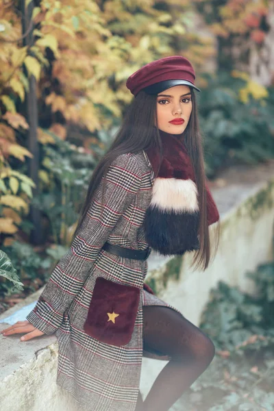 Joven hermosa chica con el pelo muy largo con abrigo de invierno y gorra en el fondo de las hojas de otoño — Foto de Stock