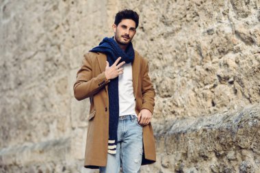 Sokakta kışlık kıyafetler giyen genç bir adam..