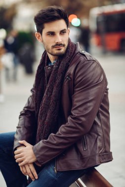 Kentsel bir bankta oturan düşünceli genç adam.
