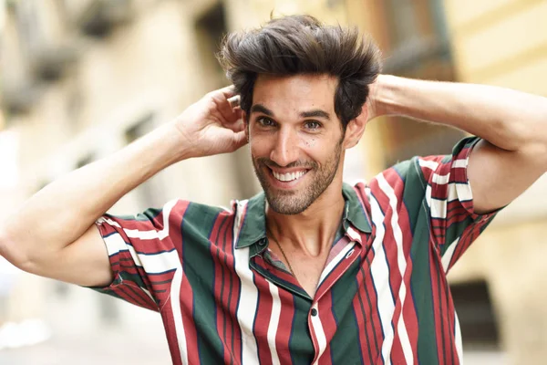 Giovane uomo sorridente con capelli scuri e acconciatura moderna che indossa abiti casual all'aperto — Foto Stock