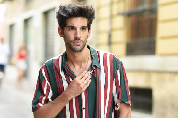 Attraente giovane uomo con i capelli scuri e acconciatura moderna che indossa abiti casual all'aperto — Foto Stock