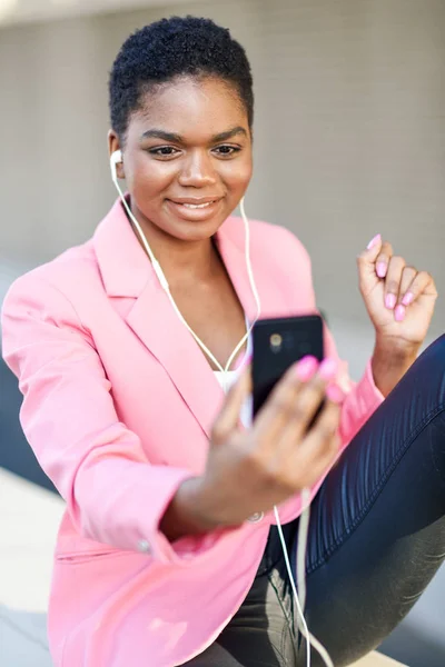 Svart affärskvinna sitter utomhus tala via videokonferens med sin smartphone. — Stockfoto