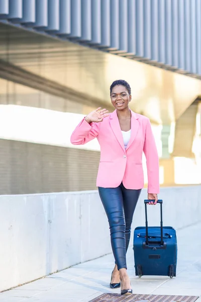 Donna nera che cammina con borsa da viaggio con giacca rosa . — Foto Stock