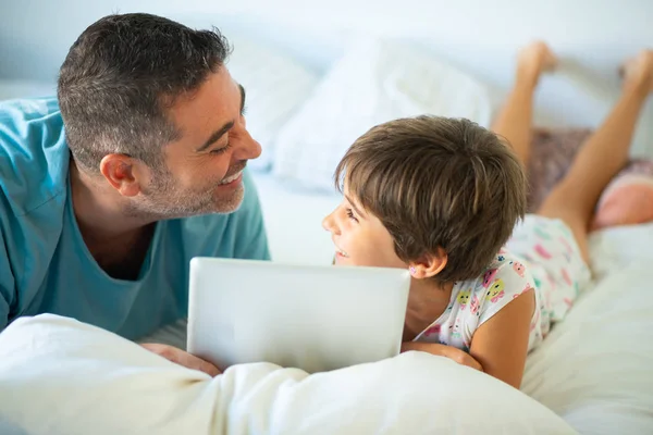 Père d'âge moyen avec sa fille de huit ans en utilisant une tablette numérique dans la chambre . — Photo