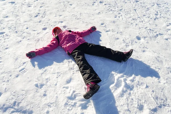 Holčička, která dělá sněhovou andělku na sněhových šatech — Stock fotografie