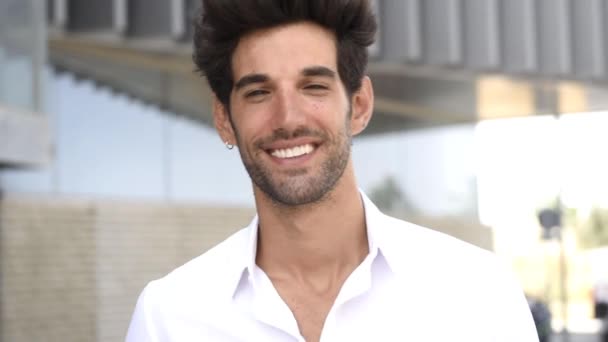 Jeune homme souriant à la caméra portant des vêtements décontractés avec une coiffure moderne . — Video