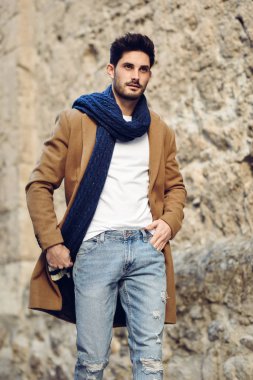 Sokakta kışlık kıyafetler giyen genç bir adam..