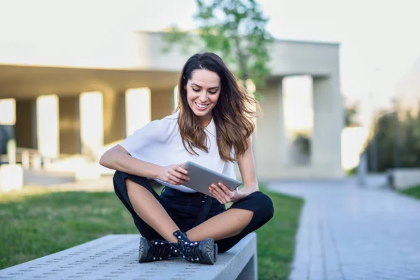 Medelålders kvinna som använder digital Tablet sittande utomhus i Urban bakgrund. — Stockfoto