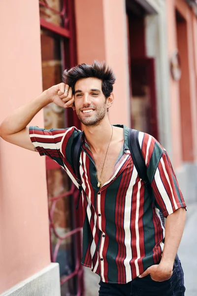 Uśmiechnięty młody człowiek z ciemnymi włosami i nowoczesną fryzurą ubrany w ubranie na zewnątrz — Zdjęcie stockowe