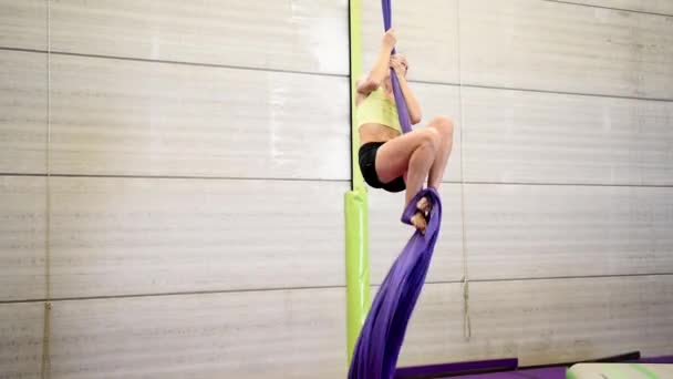 Genç kızıl saçlı kadın bir spor salonu içinde akrobatik kumaşlar ile hava jimnastik akrobasi yapıyor. — Stok video