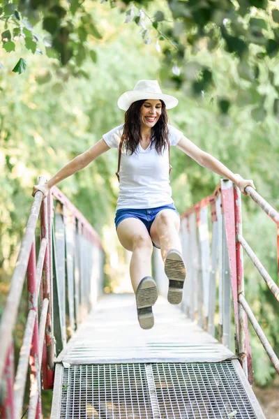 Woman with backpack standing on rural bridge. — Stock Photo, Image