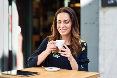 Orta yaşlı bir kadın bir şehir kafe barda kahve içiyor.