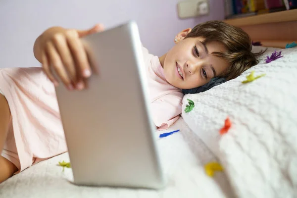 Nettes Mädchen mit einem Tablet-Computer in ihrem Schlafzimmer — Stockfoto