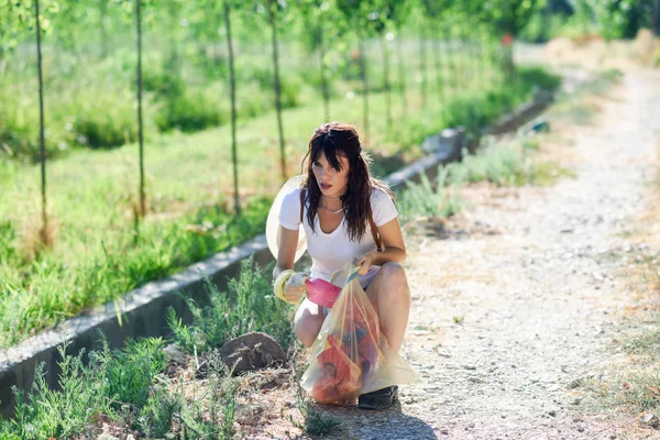 Frau sammelt mit der Hand den Grasmüll auf dem Land — Stockfoto