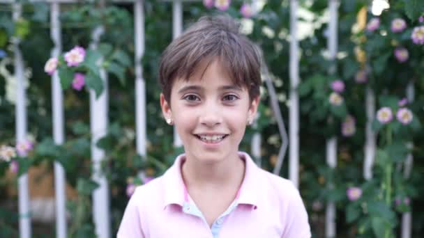Acht jaar oud meisje glimlachend en waait een kus buitenshuis — Stockvideo