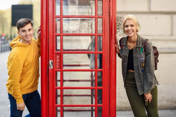 Jeune couple d'amis près d'une cabine téléphonique rouge britannique classique — Photo