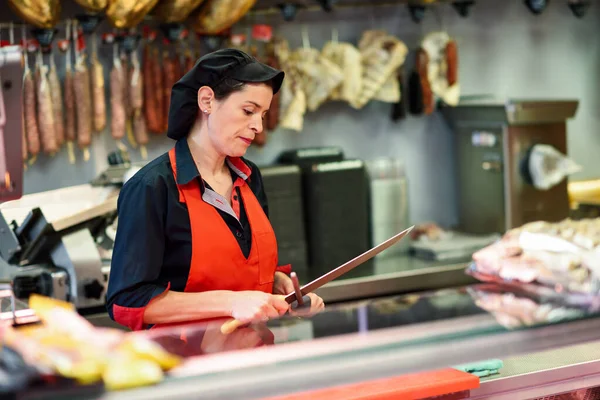 Carniceiro afiando uma faca em um açougue — Fotografia de Stock