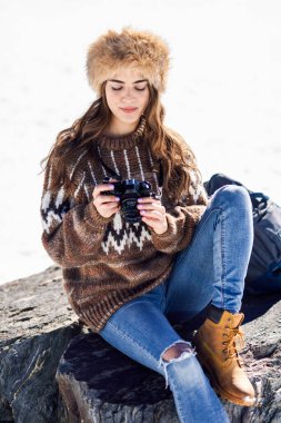 Karlı dağlarda fotoğraf çeken genç bir kadın.