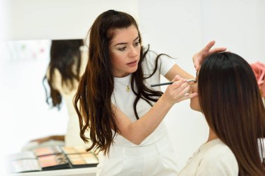 Makyöz Afrikalı bir kadına göz farı sürüyor. Güzellik merkezinde..