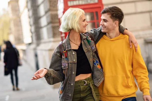 Young couple of friends near a classic British red phone booth — Stock Photo, Image