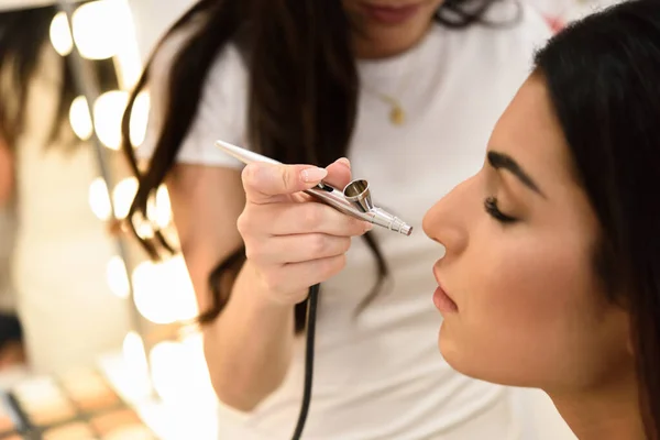 Maquiagem artista usando o aerógrafo fazendo um airbrush compõem — Fotografia de Stock