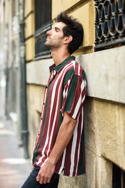 Attraktiver junger Mann mit dunklen Haaren und moderner Frisur in lässiger Kleidung im Freien — Stockfoto