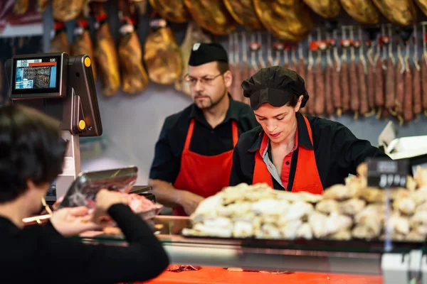 Macellai che assistono un cliente in una macelleria — Foto Stock