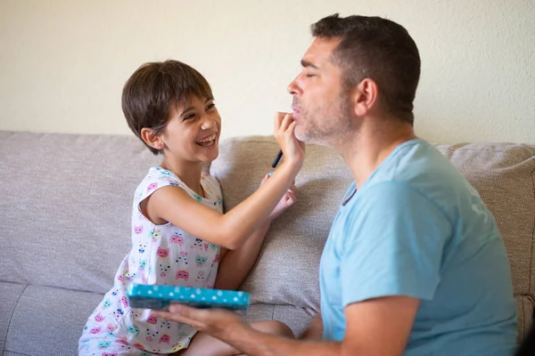 Pequeña hija linda haciendo maquillaje a su padre — Foto de Stock