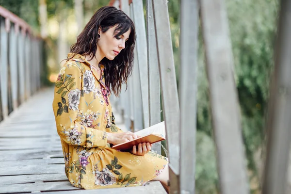 Молодая женщина читает книгу на сельском мосту . — стоковое фото