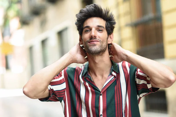 Aantrekkelijke jonge man met donker haar en moderne kapsel dragen van casual kleding buitenshuis — Stockfoto