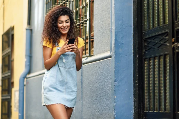 Nordafrikanerin läuft auf der Straße und schaut auf ihr Smartphone — Stockfoto