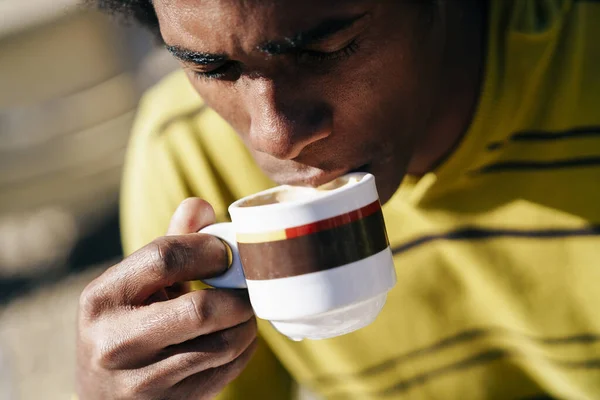 Hombre negro disfrutando del café en la cafetería mientras se sienta a la mesa al aire libre — Foto de Stock