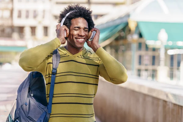 Černoch poslouchá hudbu s bezdrátovými sluchátky okružní v Granadě — Stock fotografie
