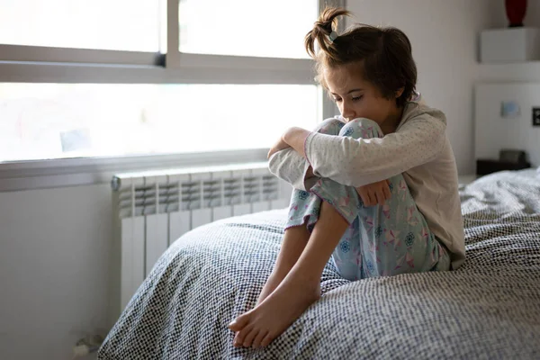 Gadis sembilan tahun duduk di tempat tidur bosan dengan kurungan — Stok Foto