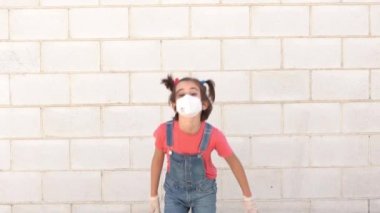 Koronavirüse karşı koruyucu maske takarak atlayan çocuk.