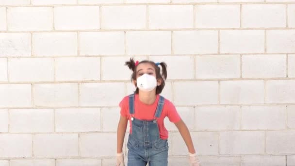 Niña saltando con una máscara de protección contra el coronavirus — Vídeo de stock